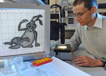 Die vermutlich kleinsten Osterhasen der Stadt - David Sylla, Wissenschaftlicher Mitarbeiter der Professur Mikrofertigungstechnik, benötigt ein Mikroskop, um den Mikro-Osterhasen in die Augen sehen zu können. 