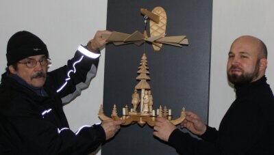 Die Zeit der Pyramiden beginnt mit Verspätung - Peter Laube (links) und Christian Landrock platzieren eine traditionelle Hängepyramide mit drei Figuren und einem geschnitzten Baum als Achse in der Mitte in der Ausstellung. 
