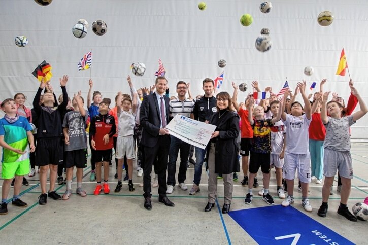 Diesterweg holt WM nach Plauen - Start frei für die Mini-WM der Grundschulen: Plauens Sport- und Kulturbürgermeister Tobias Kämpf (Mitte, links) unterstützt das Hallen-Fußballturnier genauso wie Kai Zimmermann vom Kreissportbund Vogtland (Mitte, Zweiter von links). Mandy Wolf (Mitte, rechts) übergab einen Scheck über 1000 Euro für die Prämierung der besten Fanblöcke. Organisator ist Tommy Färber (Mitte, Zweiter von rechts) vom Plauener Diesterweg-Gymnasium. 