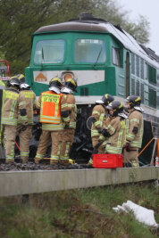 Drei Menschen sterben bei Zusammenstoß mit Güterzug - Rettungskräfte stehen an der Bahnstrecke bei Lohma (Thüringen) vor der Lokomotive eines Güterzugs. Beim Zusammenstoß des Güterzugs mit einem Auto sind drei Menschen ums Leben gekommen.