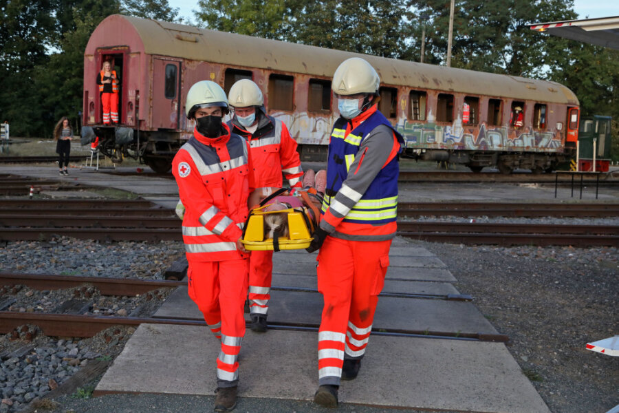 Helfer bringen bei der Übung eine verletzte Person aus dem Eisenbahnwagen. 