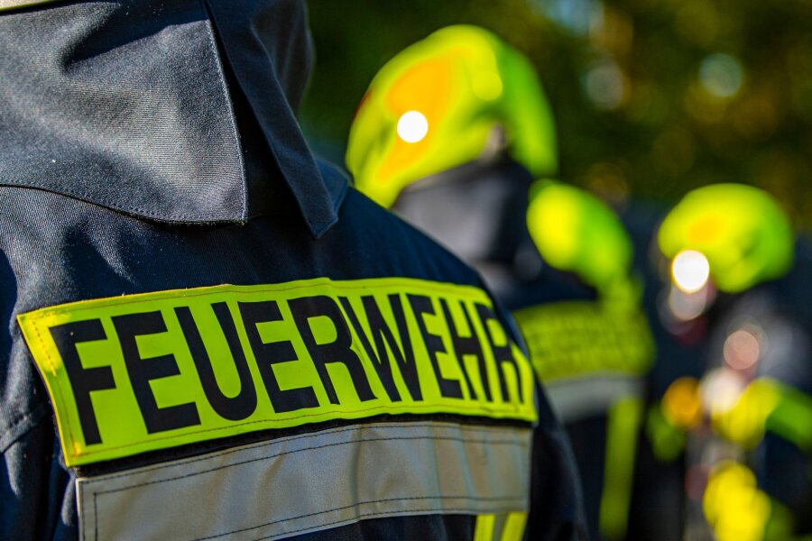 E-Autos in Leipzig in Brand gesetzt: 120.000 Euro Schaden - Feuerwehrleute stehen zusammen, um den Einsatz zu besprechen.