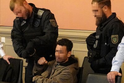 Ehefrau mit elf Messerstichen getötet: Urteil des Landgerichts Zwickau jetzt rechtskräftig - Justizbeamte bringen den Angeklagten in den Gerichtssaal.