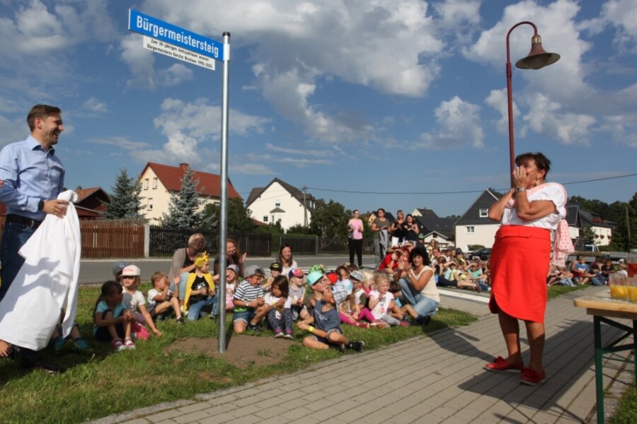 Ein eigener Gehweg für "Frau Bürgermeister" - In Hartmannsdorf gibt es seit Freitag einen "Bürgermeistersteig" zu Ehren von Bürgermeisterin Kerstin Nicolaus (CDU). Christfried Nicolaus, Anwärter für das Amt, enthüllte das Schild, das das Wirken seiner Mutter über drei Jahrzehnte für ihr Dorf würdigen soll. 