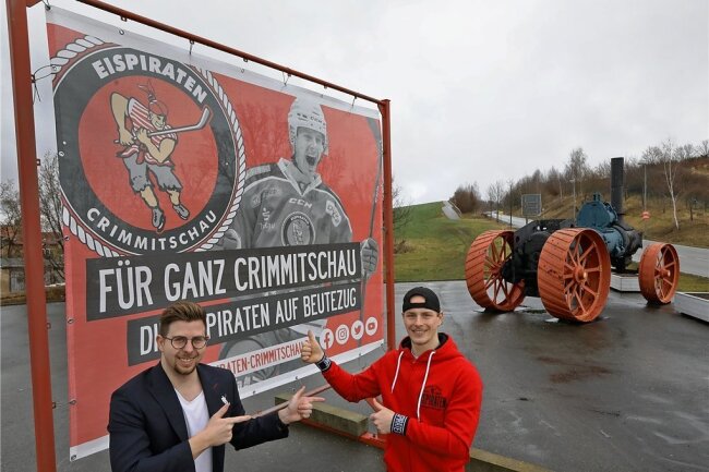 Ein Eispiraten-Stürmer, der am Kreisverkehr über ein Tor jubelt - Sie freuen sich über das Plakat: Medienchef Aaron Frieß (links) und Will Rudert. 