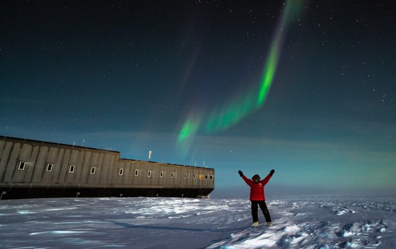 Polarlichter fotografieren. Das macht der Erdmannsdorfer Martin Wolf gerne in seiner Freizeit am Südpol. Hier ein Selbstporträt mit seiner Arbeitsstelle im Hintergrund: die Amundsen-Scott-Antarktisstation.
