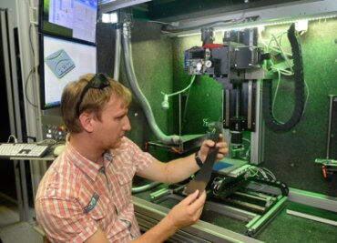 Im Laserinstitut der Hochschule Mittweida prüft Stefan Mauersberger ein Stück carbonfaserverstärkten Kunststoff. In Hochgeschwindigkeit werden hier Oberflächen bearbeitet und Materialen getrennt. 