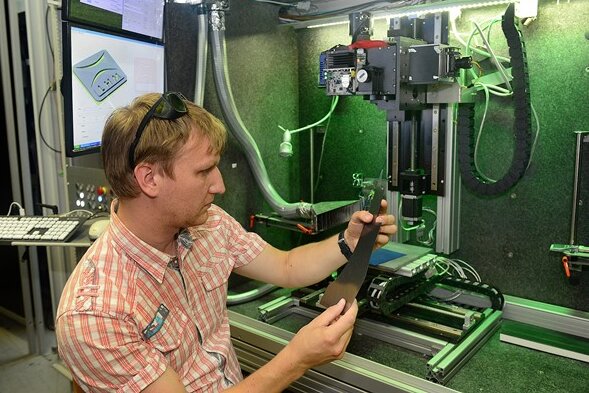 Im Laserinstitut der Hochschule Mittweida prüft Stefan Mauersberger ein Stück carbonfaserverstärkten Kunststoff. In Hochgeschwindigkeit werden hier Oberflächen bearbeitet und Materialen getrennt. 