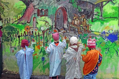 Ein Gemälde für „Waldwichtel“ in Halsbrücke: Berthold Krahl gestaltet großes Gemälde für kleine Kinder - Als wären sie Teil des Bildes: Vier „Waldwichtel“ bei der Arbeit verschmelzen fast mit dem Wandbild.