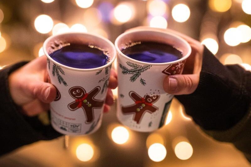            Zwei Besucherinnen eines Weihnachtsmarktes stoßen mit Glühwein an.
