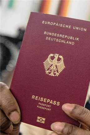 Einbürgerung soll leichter werden: Diese Änderungen sind vorgesehen - Eine aus Indien stammende Frau hält ihren neuen Pass in die Kamera. Nach Deutschland eingewanderte Menschen, sollen künftig - sofern sie ein qualifiziertes Aufenthaltsrecht haben - nach fünf, nicht wie bisher nach acht Jahren eingebürgert werden können.