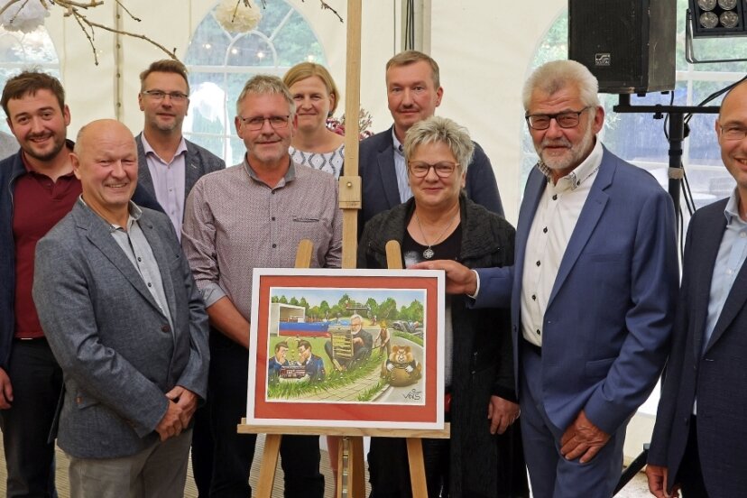 Die Bietergemeinschaft aus Reihen der Stadtverwaltung und des Stadtrates verabschiedete Bernd Pohlers (2. von rechts) mit der von ihr ersteigerten Karikatur von Veit Schenderlein in den Ruhestand.