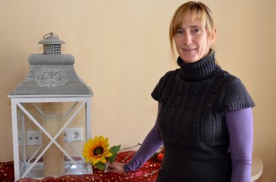 Eine Kerze und eine Blüte zur Erinnerung - Silvia Oehme mit der Laterne, in der bei Todesfällen die Kerze angezündet wird. Die Sonnenblume, auf der die Namen der Verstorbenen verewigt wird, wird derzeit von einem Tischler hergestellt.