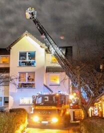 Einsätze bei zwei Schornsteinbränden - Feuerwehrleute kontrollieren den Schornstein auf dem Mehrfamilienhaus in Seifersdorf mit Hilfe einer Drehleiter.