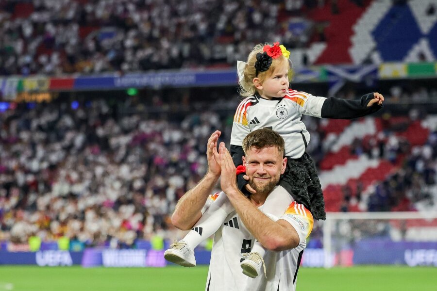 EM der Frauen und Kinder: Kraft für "Papa" und "Julsi" - Niclas Füllkrug trägt nach dem ersten EM-Spiel der Deutschen seine Tochter Emilia durch das Stadion.