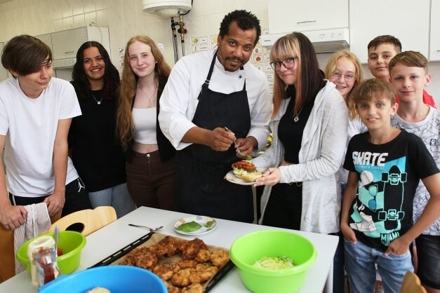 Ricardo Basjan (M.) kochte mit Mädchen und Jungen der Oberschule Beierfeld: Gemeinsam mit Shania Zenker (16) aus Beierfeld richtet er das Popeyes Chicken Sandwich an.