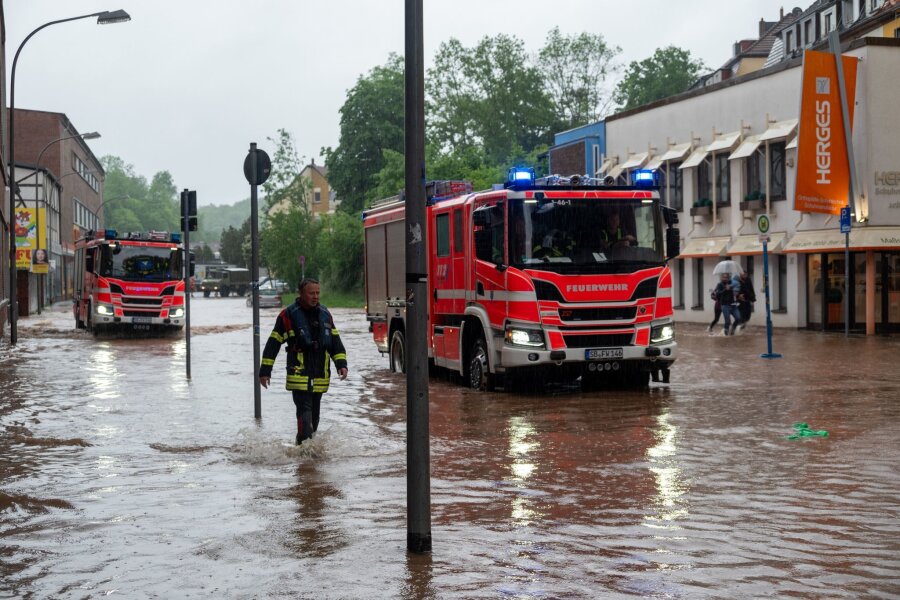 Erdrutsche und Überflutungen nach Dauerregen im Saarland - Feuerwehrleute bewegen sich durch das Hochwasser in Saarbrücken.