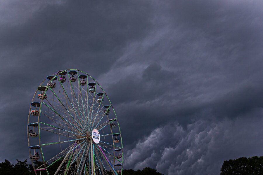 Erneut Unwetter über Deutschland - Dunkle Regenwolken ziehen über ein Riesenrad auf dem Gelände des Hurricane-Festivals in Scheeßel hinweg.
