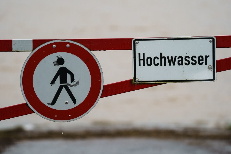 Erste Hochwasserwarnungen für Flussgebiete in Sachsen - Ein Hochwasser-Schild steht an einem überfluteten Feld.