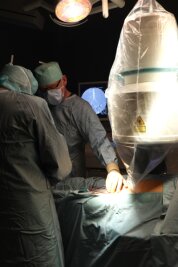 Erste Hybridoperation in Mittweida durchgeführt - Chefarzt Dr. Wurlitzer (li.) und Oberarzt Dr. Schnee (2.v.li.) während der Gefäßoperation. Rechts ist das Röntgengerät zu sehen, im Hintergrund sieht man auf dem Monitor das Röntgenbild der Gefäße.