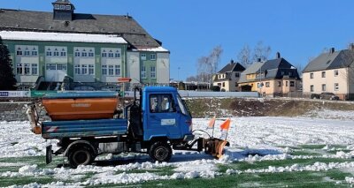 Erzgebirgs-Derby steht auf der Kippe - Hilfe vom Bauhof: Ein Multicar beseitigte am Donnerstag den Kunstrasen in Thalheim von den gröbsten Schneemassen. 
