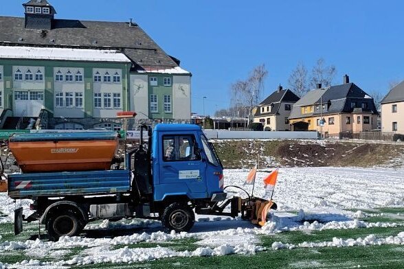 Erzgebirgs-Derby steht auf der Kippe - Hilfe vom Bauhof: Ein Multicar beseitigte am Donnerstag den Kunstrasen in Thalheim von den gröbsten Schneemassen. 
