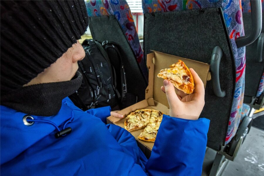 „Essen verboten. Wenn du dich nicht dran hältst, fliegst du raus“: Busunternehmen aus dem Erzgebirge greift durch - Ein Schüler aus dem Erzgebirge isst im Schulbus nach Hause noch schnell eine Pizza. So wie auf diesem gestellten Foto passiert das öfter.