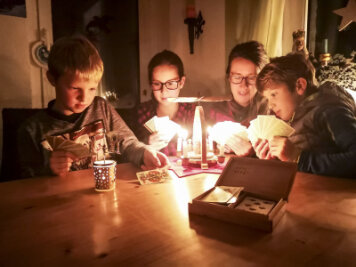 Etwa 4500 Haushalte im Erzgebirge am Donnerstag ohne Strom - Malte (11), Kira (14), Mutter Katja und Kalle (9) aus Geyer spielen zusammen Karten und machen das Beste aus dem Stromausfall.