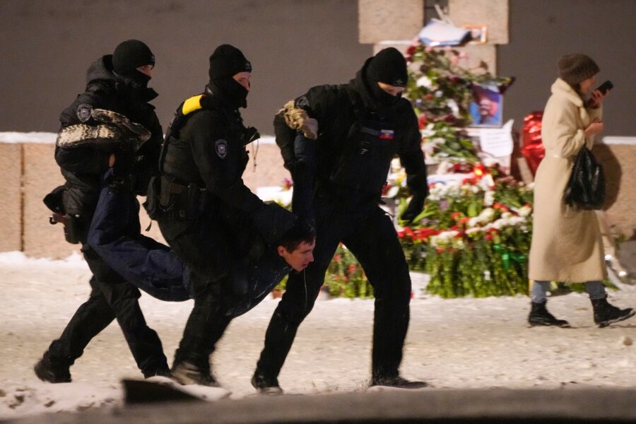 EU beschließt Rahmen für Russland-Sanktionen - Polizeibeamte halten einen Mann fest, der Blumen zu Ehren von Alexej Nawalny an einem Denkmal für die Opfer der sowjetischen Unterdrückung in St. Petersburg niedergelegt hat.