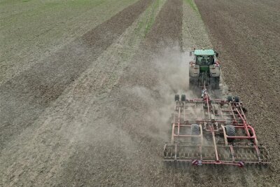 EU-Prämien für Bauern: Sachsens Nachbarländer wollen Gelder noch dieses Jahr auszahlen - Ein Traktor lockert mit einer Egge den Boden auf.
