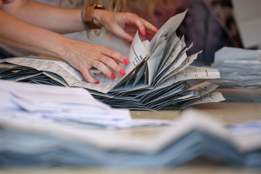 Europawahl: AfD zufrieden, Grüne und SPD enttäuscht - Eine Wahlhelferin legt Stimmzettel zur Stimmenauszählung der Briefwahlstimmen zur Europawahl auf einem Stapel.