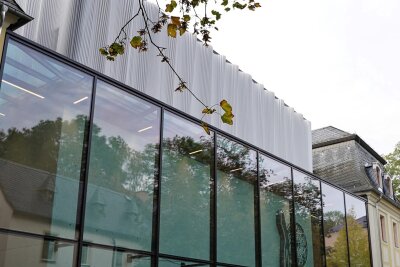 Fabrik der Fäden vor Eröffnung am 12. November: Textilmuseum wirbt mit Banner quer über dem Postplatz in Plauen - Futuristisch: Das Metallkleid auf dem Glaskomplex zeigt Ähnlichkeiten zu Textilem – darum geht's im Museum.