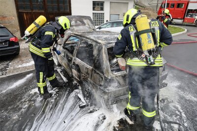 Fahrzeugbrand im Erzgebirge: Feuerwehr rückt zu Einsatz an einer Hobbywerkstatt aus - Der ins Freie geschobene VW brannte aus. Die Feuerwehr setzte zum Löschen ein Wasser-Schaum-Gemisch ein.