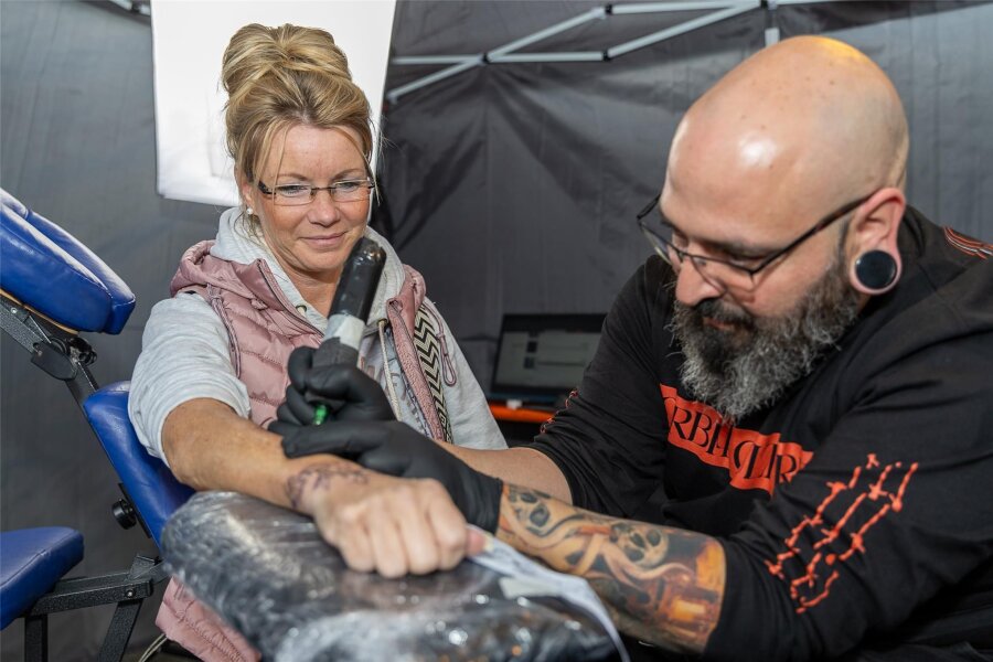 Falken Rock: Partygäste lassen sich Tattoos stechen - Tätowierer Jose de Sola aus Spanien tätowiert Nancy Hauffe.
