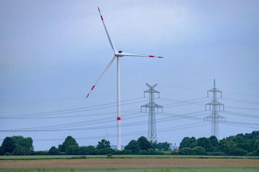 Fast 60 Prozent Strom aus erneuerbaren Quellen - Eine Windkraftanlage und Hochspannungsleitungen in NRW.