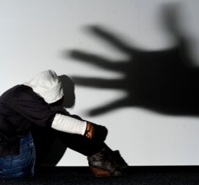 Fast immer lebenslänglich für das Opfer - Ein Mädchen sitzt vor einer Wand, auf der groß der Schatten einer Hand zu sehen ist. Diese steht symbolisch für die Gefahr durch Verbrecher. Der Weiße Ring unterstützt auch Opfer schwerer Straftaten. 