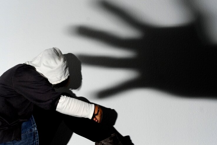 Fast immer lebenslänglich für das Opfer - Ein Mädchen sitzt vor einer Wand, auf der groß der Schatten einer Hand zu sehen ist. Diese steht symbolisch für die Gefahr durch Verbrecher. Der Weiße Ring unterstützt auch Opfer schwerer Straftaten. 