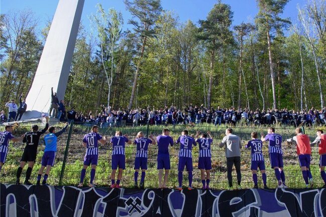 Die Auer Spieler feiern nach dem Spiel mit Fans, die sich außerhalb des Stadions im Wald versammelt haben.