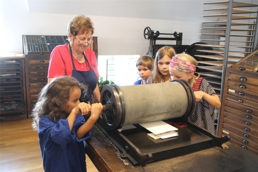 Ferienkurs in der Druckerwerkstatt in Oederan - Hermine, Alexandra, Pia und Lisbeth (v. l.) walzen das Papier, damit es die Druckerschwärze annimmt.