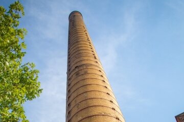 Der markante 70 Meter hohe Ziegel-Schornstein ist das Erkennungszeichen des Heizkraftwerkes auf dem Gelände der Alten Baumwolle. Hier wird die Fernwärme für große Teile der Stadt produziert. 