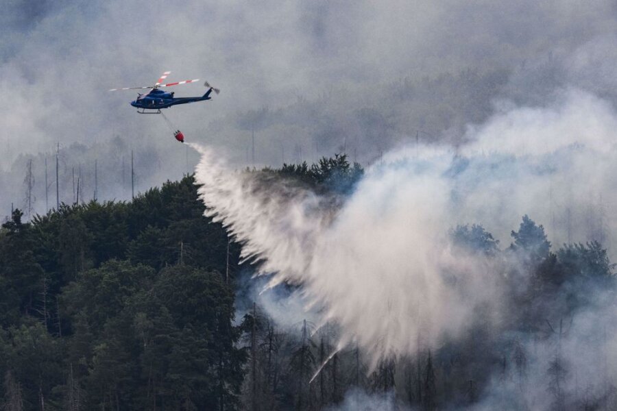 Mit einem Hubschrauber wird ein Waldbrand gelöscht.