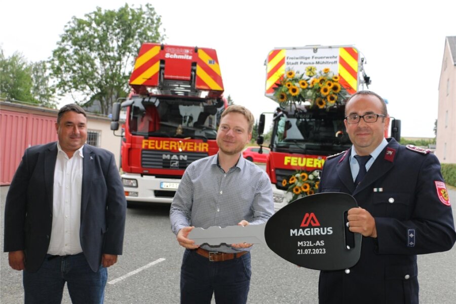 Feuerwehr Pausa-Mühltroff bekommt lang ersehnte neue Drehleiter - Gemeindewehrleiter Ralf Weber hat den symbolischen Schlüssel von Bürgermeister Michael Pohl erhalten, dieser wiederum bekam ihn von Falk Lehmann (links) von der Firma Magirus. Links die alte, rechts die neue Drehleiter, versehen mit Sonnenblumen.