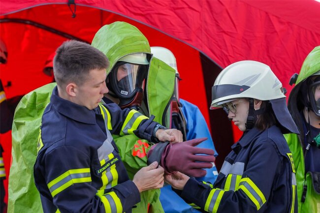 Feuerwehrleute streifen sich Chemieschutzanzüge über: Im Gewerbegebiet in Glauchau wird der Ernstfall geprobt - Mit vier verschiedenen Handschuhen und mit Schutzanzügen sind die Feuerwehrleute in ihre Übung gegangen.