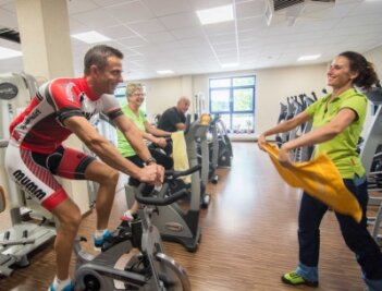 FFZ: Fitnessprofis stellen eigene Teams - Rico Mudrak macht sich auf dem Spinning-Rad fit. Handtuchwedeln hilft gegen das Schwitzen, meint Sandra Mudrak (rechts).