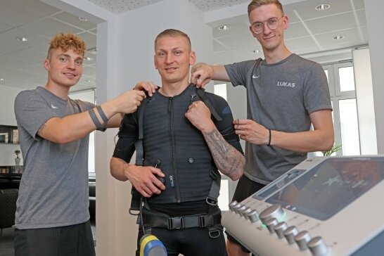 Fitnessstudio-Eröffnung trotz Pandemie - André Herold (l.) und Likas Dörken (r.) rüsten Marc-Philipp Zimmermann mit der EMS-Technik aus. 