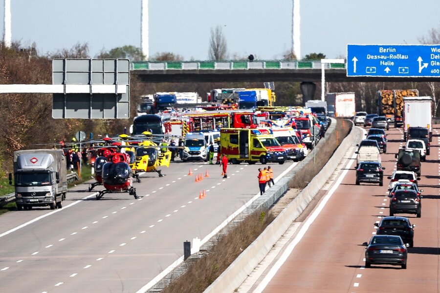 Flixbus-Unglück bei Leipzig auf der A9: Mindestens ein Toter und viele Verletzte - Einsatzfahrzeuge und Rettungshubschrauber stehen auf der A9 an der Unfallstelle.