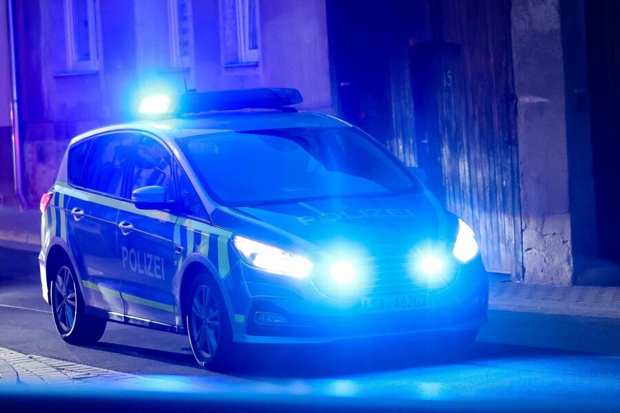 Frau stürzt mit Fahrrad - Kind schwer verletzt in Klinik - Ein Fahrzeug der Polizei fährt mit Blaulicht am Abend durch eine enge Straße.