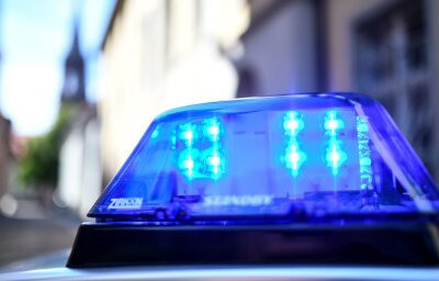 Frau tot in Freital gefunden: 51-Jähriger unter Verdacht - Ein Polizeiauto mit blinkendem Blaulicht steht vor einem Gebäude.