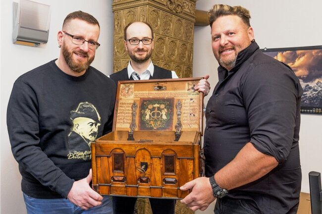 "Freie Presse"-Text über historisches Fundstück bleibt nicht ohne Folgen - Die Stadträte Frank Schubert (links) und Jörg Tobisch (rechts) koordinierten die Spendenaktion für die Innungslade. Hier zeigen sie gemeinsam mit Thomas Mauersberger das historische Stück. Die Stadt hat es sich vorab schon mal beim Verkäufer ausgeliehen.