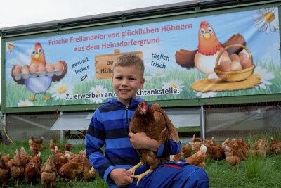 Für glückliche Hühner: Landwirt im Vogtland schafft mobile Ställe an - Stolzer Spross der Bauernfamilie: Richard Schimpfermann vor dem mobilen Hühnerstall, der vom Heinsdorfer Radweg aus mit seinem großen Werbebanner nicht zu übersehen ist.